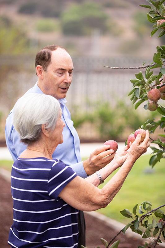 Loren picking apples with resident.